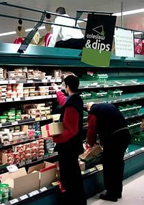 A manager sits on top of the veg display directing operations to remove Christmas decorations